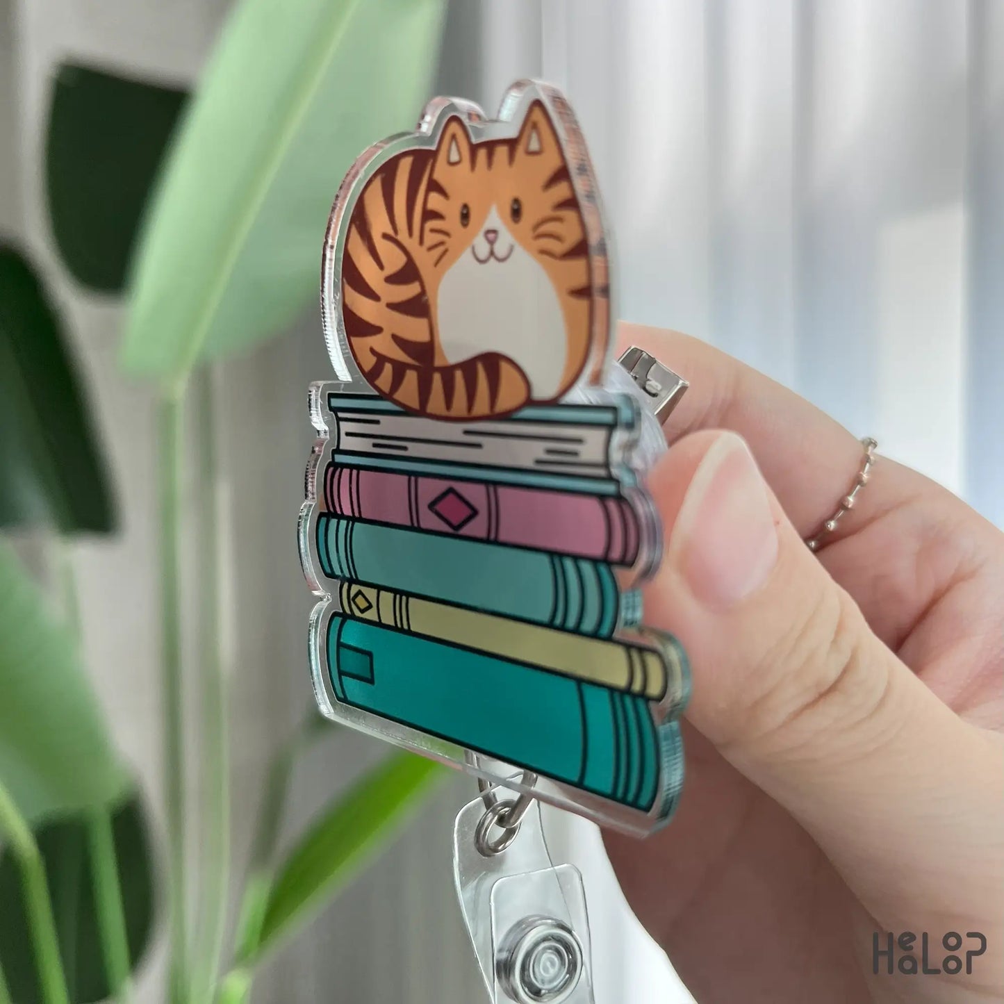 Side view of cat sitting on books retractable badge reel