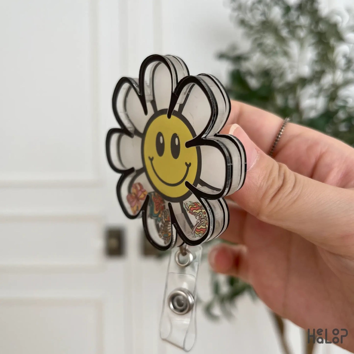 Side angle view of acrylic daisy flower badge reel with smiley face.