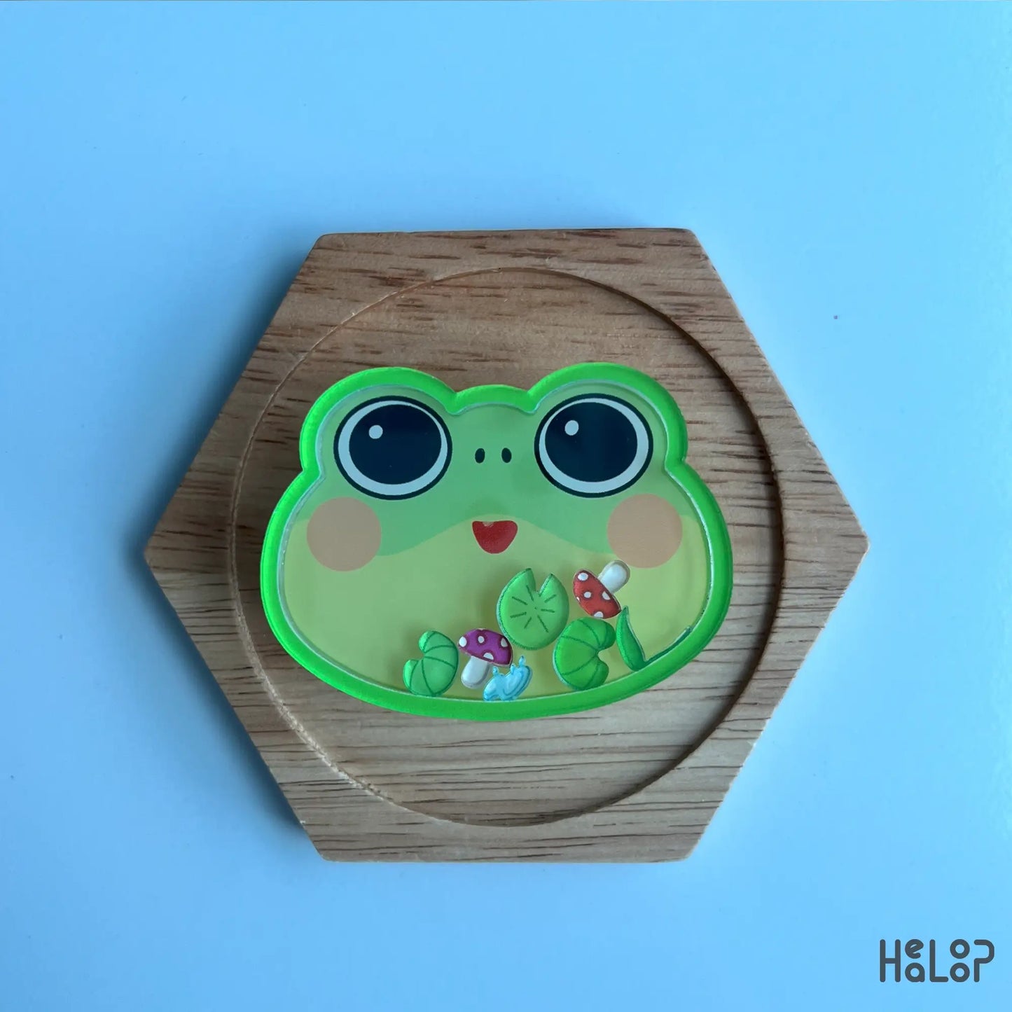 Frog phone grip displayed on wooden stand, cute acrylic design
