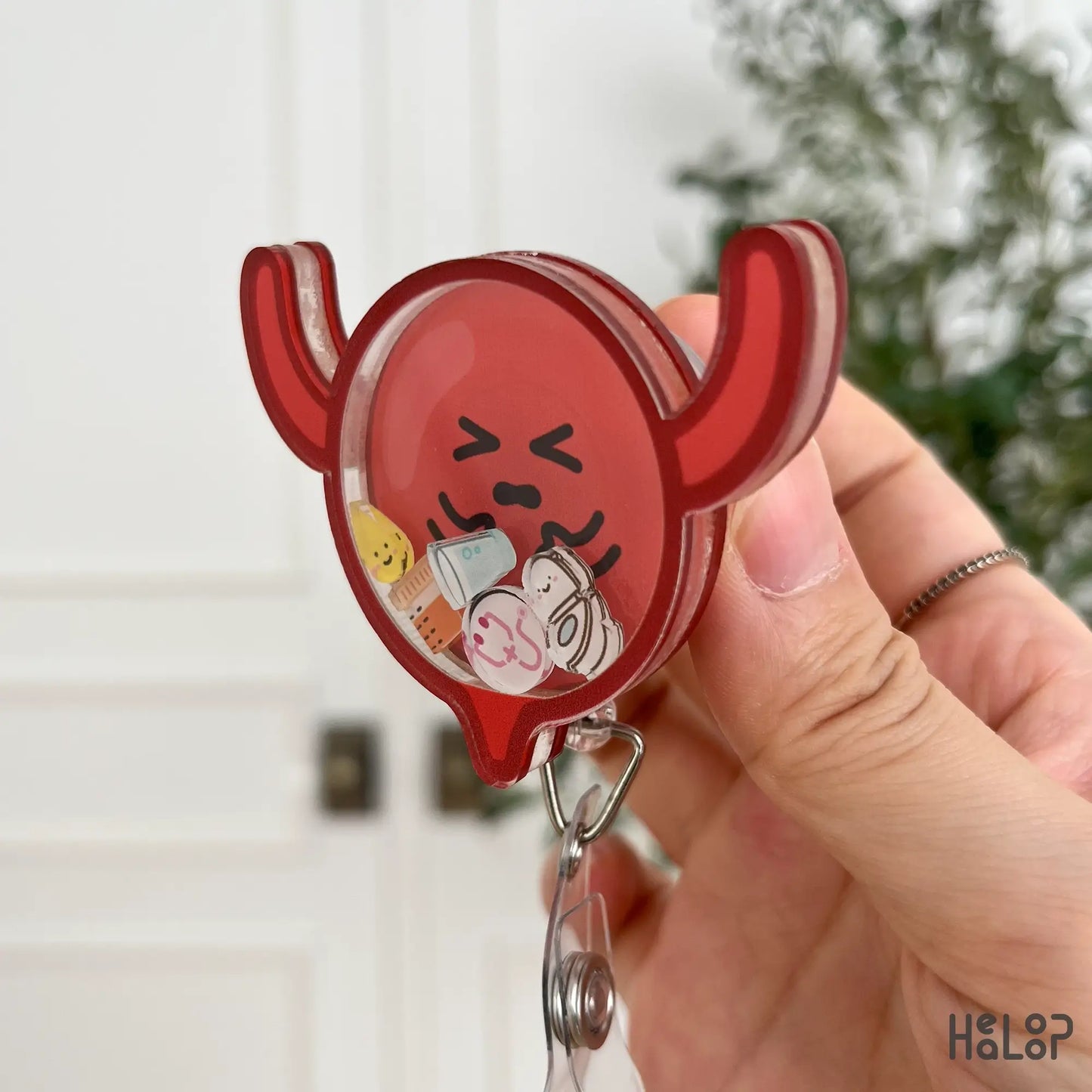 Side angle of red bladder badge reel with shaker charms and retractable clip