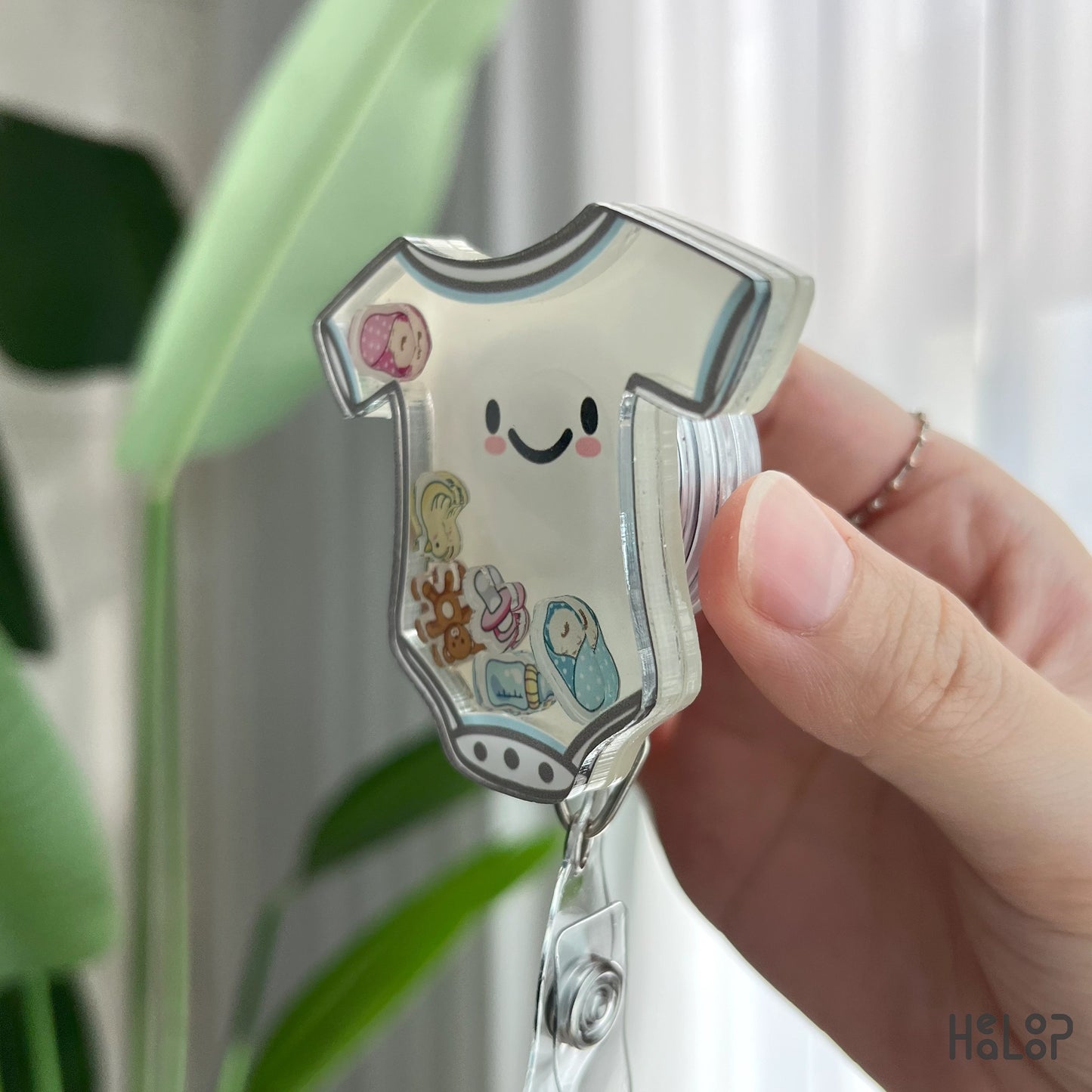 Angled side view of NICU shaker badge reel with baby onesie shape and floating charms