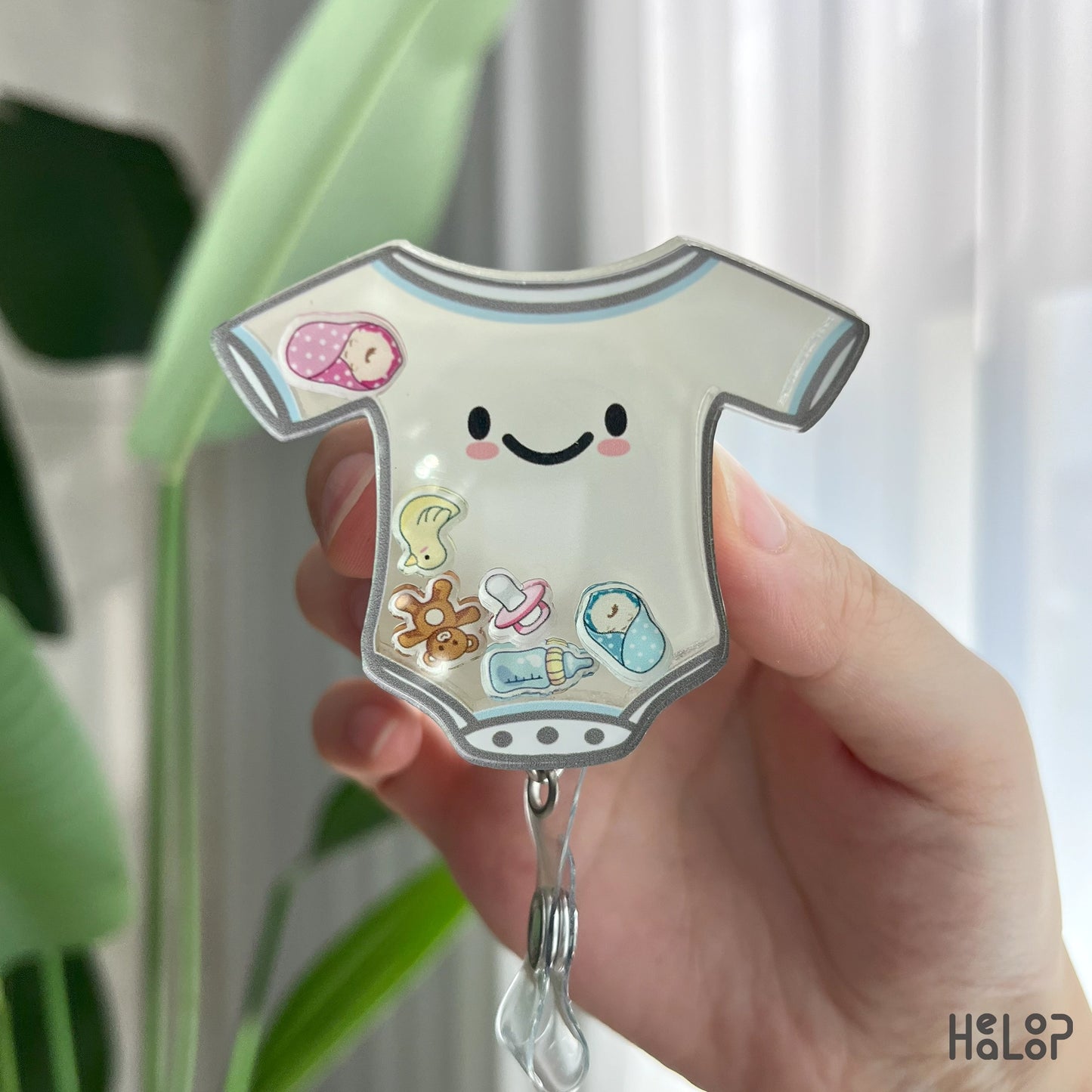 Detailed view of NICU shaker badge reel with pacifier, swaddled babies, teddy bear, and bottle