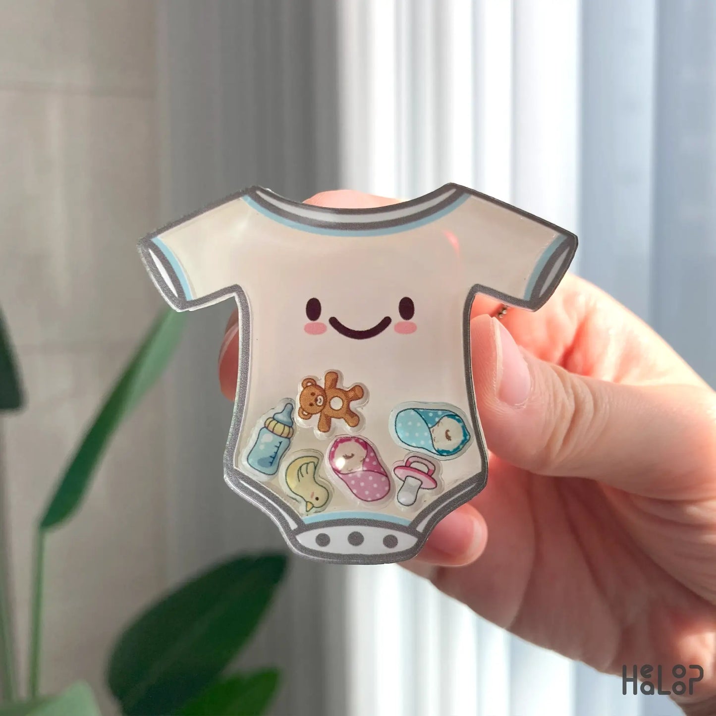 Detailed view of NICU shaker phone grip with floating baby bottle, teddy bear, and newborn charms