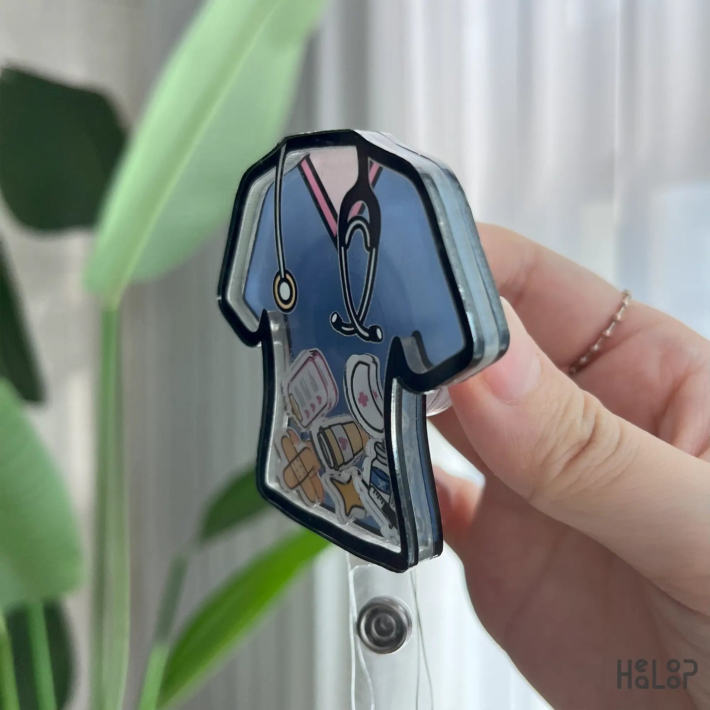 Side angle of 3D acrylic nurse shaker badge reel showing layered build and floating medical charms.