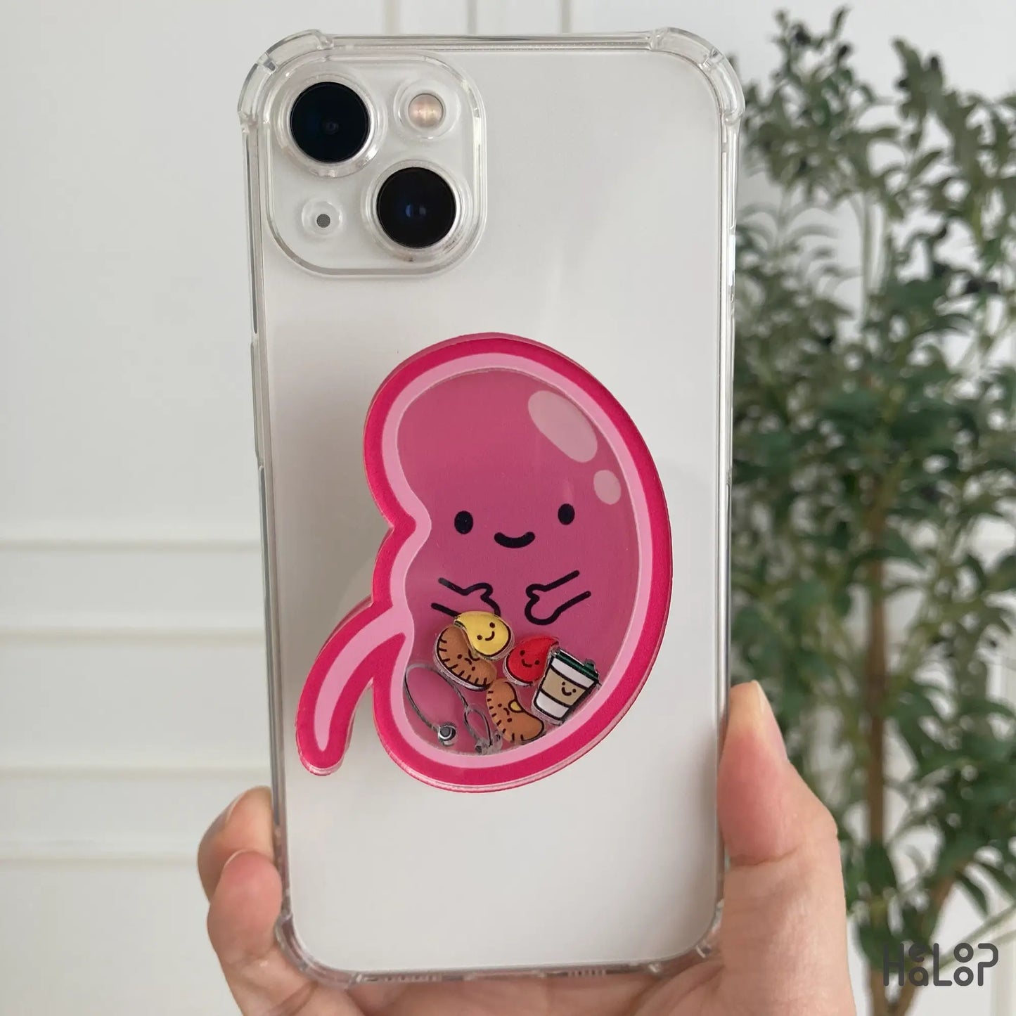 Pink kidney-shaped shaker phone grip attached to white smartphone case