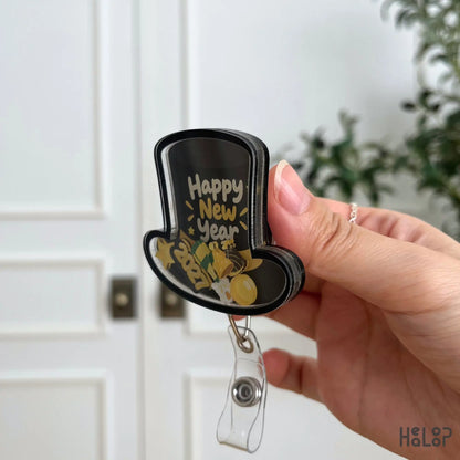 Side angle of HEALOOP New Year 2027 shaker badge reel highlighting the three-layer acrylic construction and colorful party-themed charms.