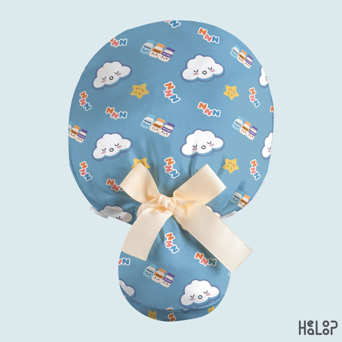 Anesthesia ponytail scrub cap in blue with sleepy clouds, yellow stars, Zzz lettering, and medication vial illustrations, featuring a cream ribbon and ponytail pouch.
