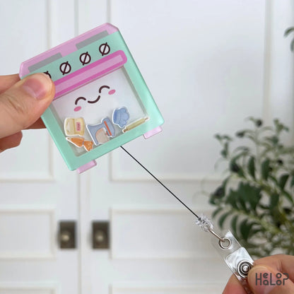 Retractable baking shaker badge holder featuring a smiling oven and interactive baking-themed charms