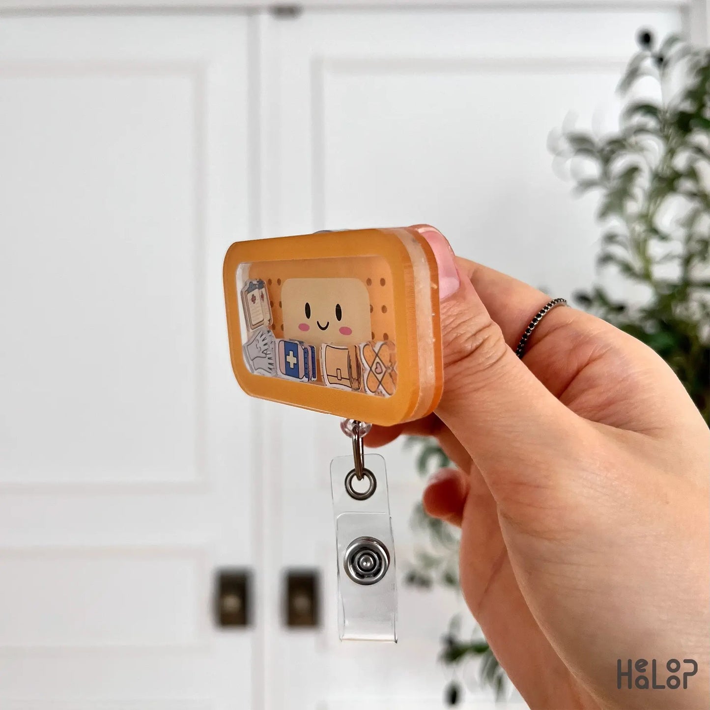 Side angle of bandage shaker badge reel displaying layered acrylic design