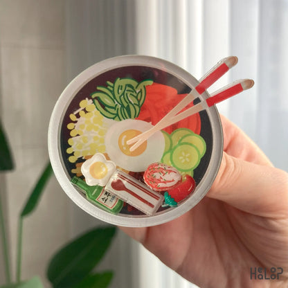 Detailed close-up of Korean bibimbap shaker phone grip with floating food charms