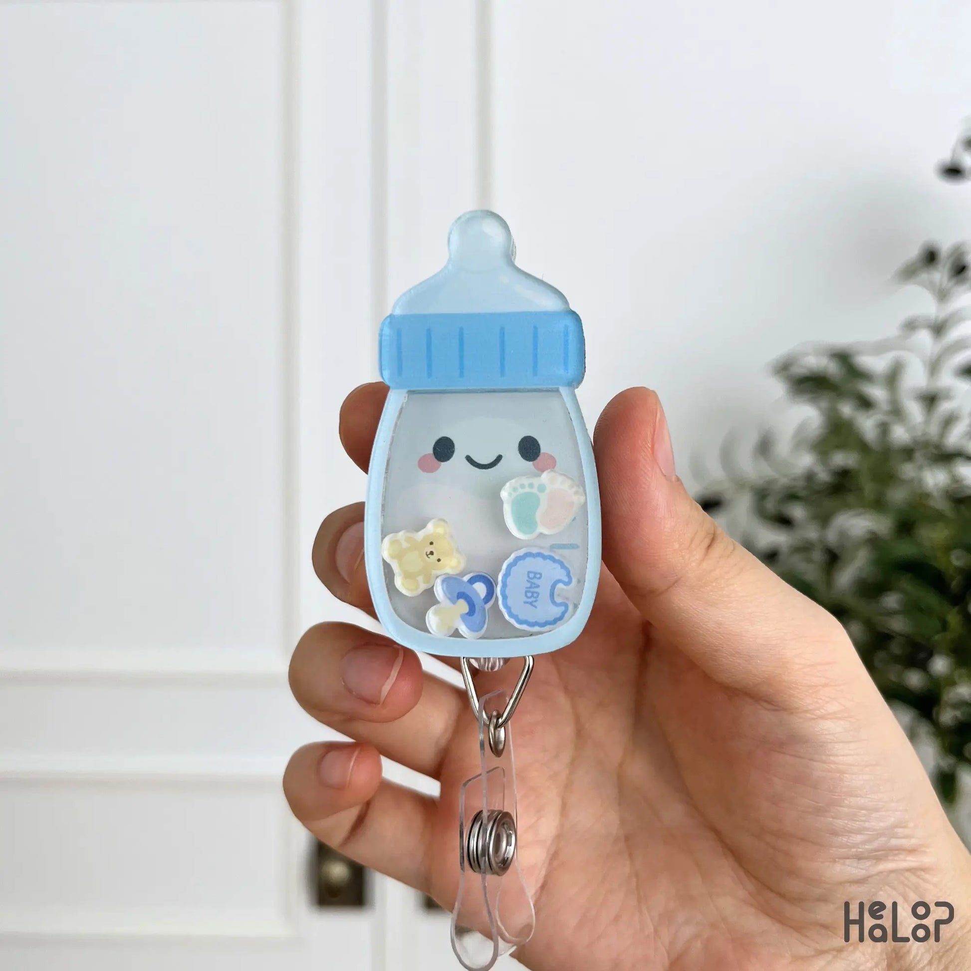 Blue Baby Bottle Shaker Badge Reel with pacifier, baby footprints, teddy bear and bib moving charms
