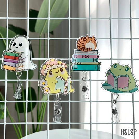 Display of bookish acrylic badge reels with ghost, frog, mushroom, and cat characters