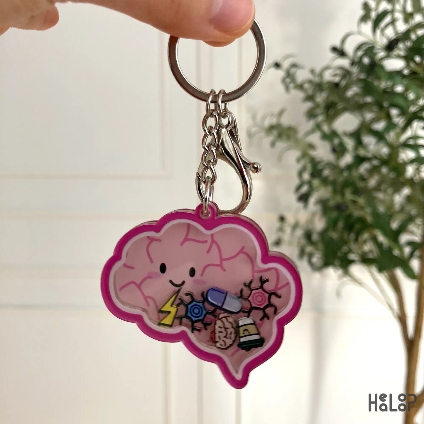 Front view of pink brain shaker keychain with neuron and pill charms.