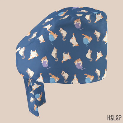 Side profile of the HEALOOP Cat Classic Scrub Cap featuring orange, white, and gray cats playing with blue and purple yarn balls on a navy blue background.