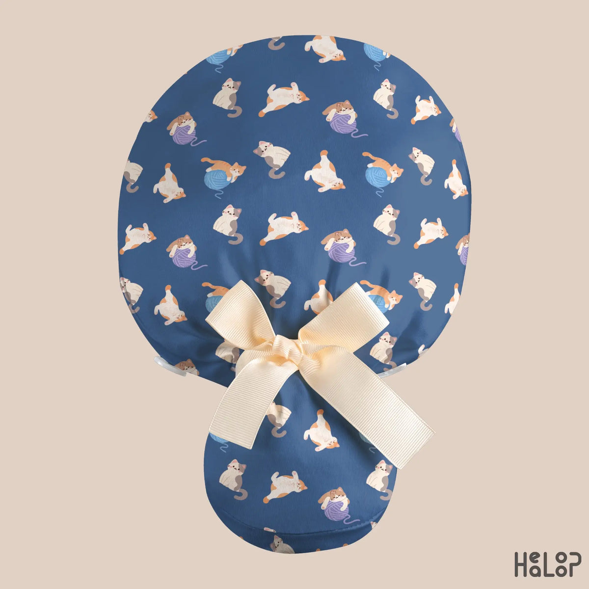 Cat Ponytail Scrub Cap shown from the back, featuring adorable cats and colorful yarn balls on navy blue fabric, with a spacious ponytail pouch and cream-colored ribbon bow.