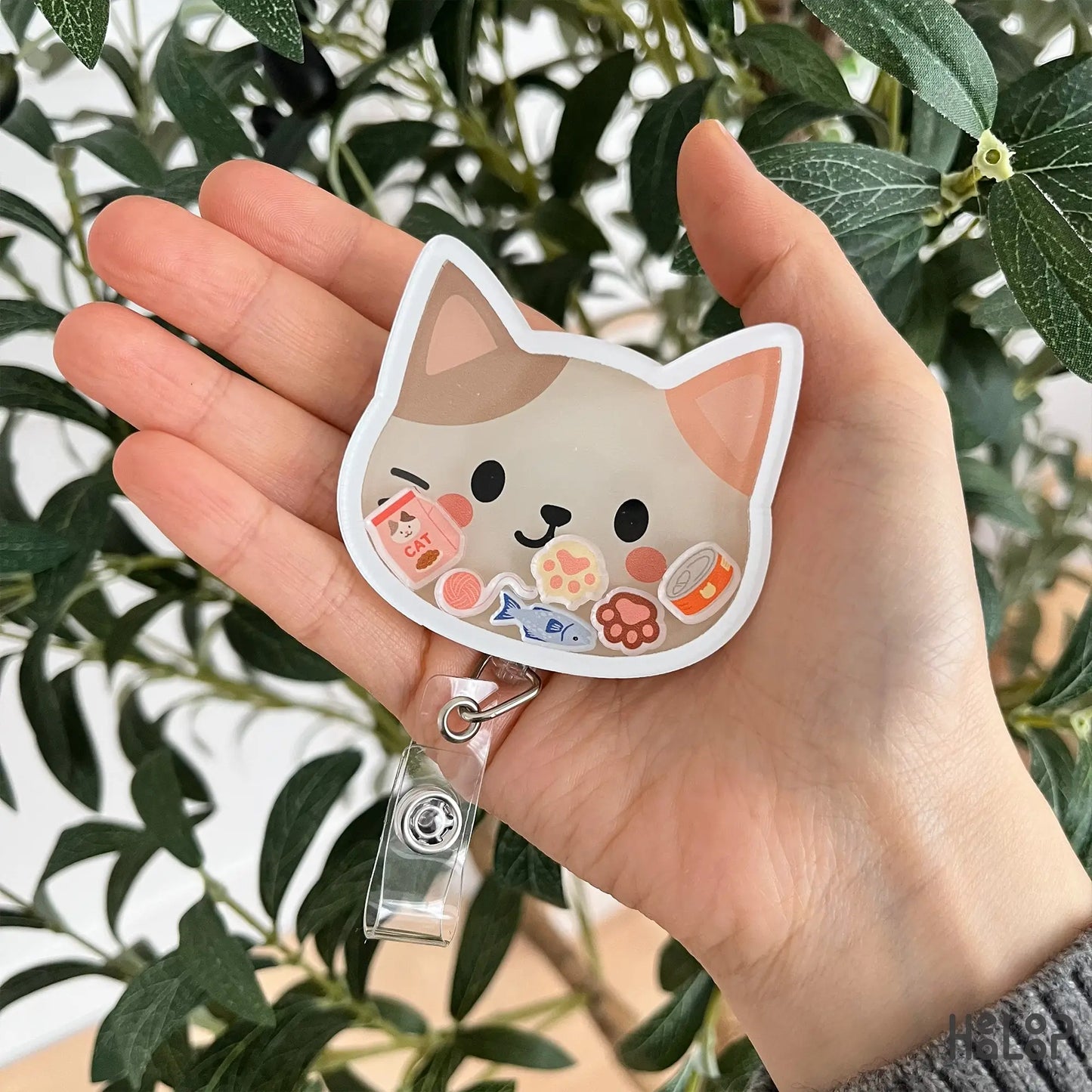 Cute cat themed shaker badge reel held in hand, ideal accessory for nurses and office staff