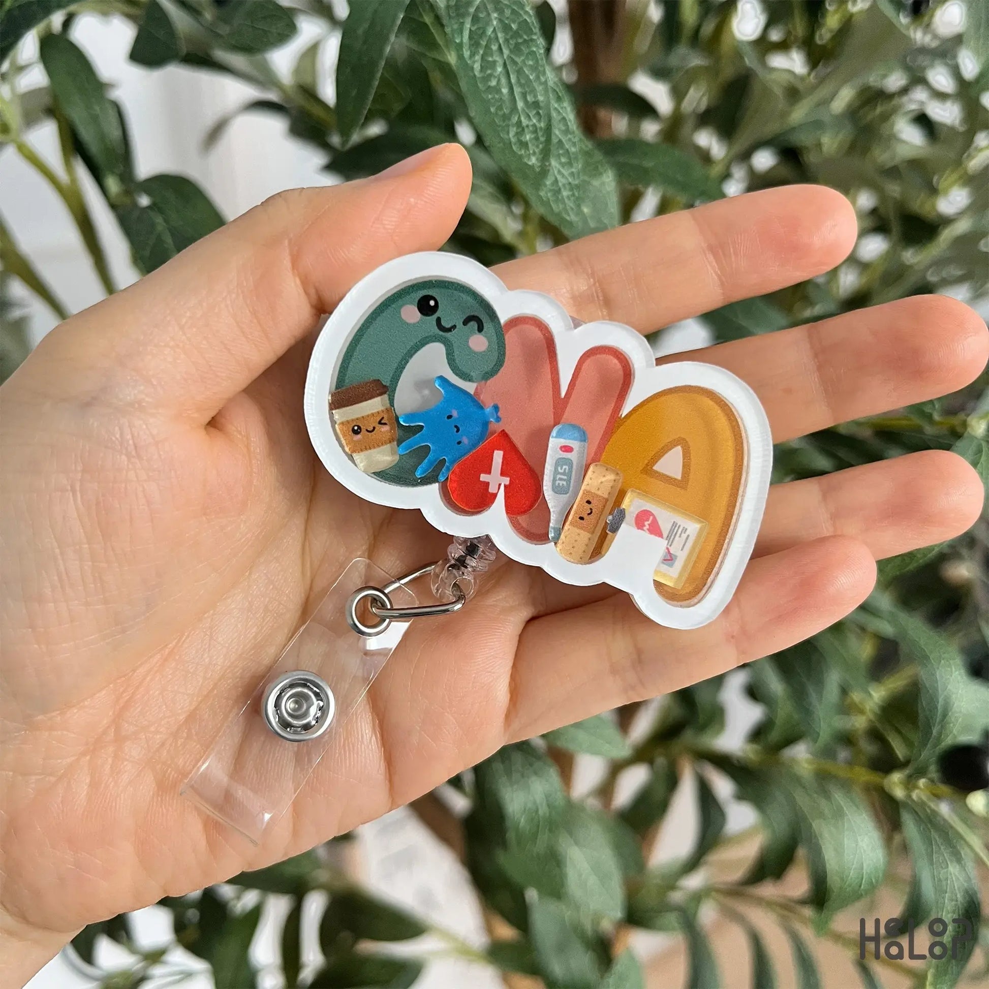 Close-up handheld CNA shaker badge reel with vibrant CNA lettering and charms.