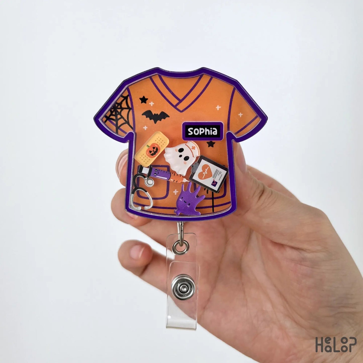 Close-up of a personalized Halloween nurse shaker badge reel with custom name and spooky healthcare charms.