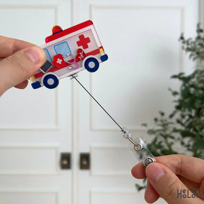 Retractable ambulance shaker badge reel with interactive medical-themed charms inside a layered acrylic design.