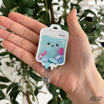 Cute IV Bag Shaker Badge Reel held in hand with smiling IV fluid bag and movable medical shaker charms for nurses and healthcare workers.