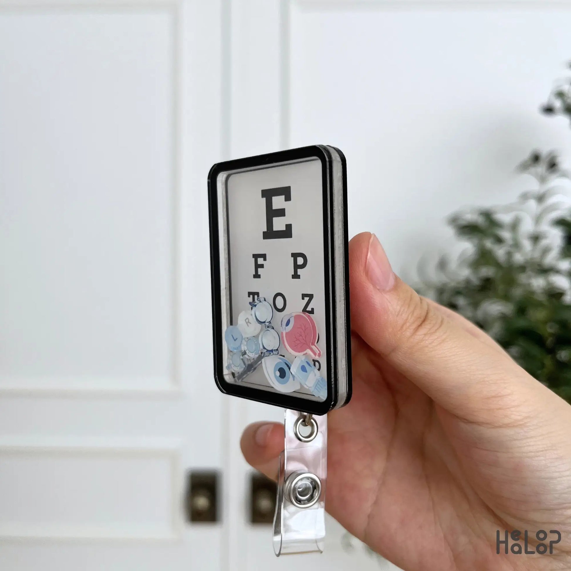 Side view of the Eye Chart Shaker Badge Reel showing its layered acrylic construction and moving charms.