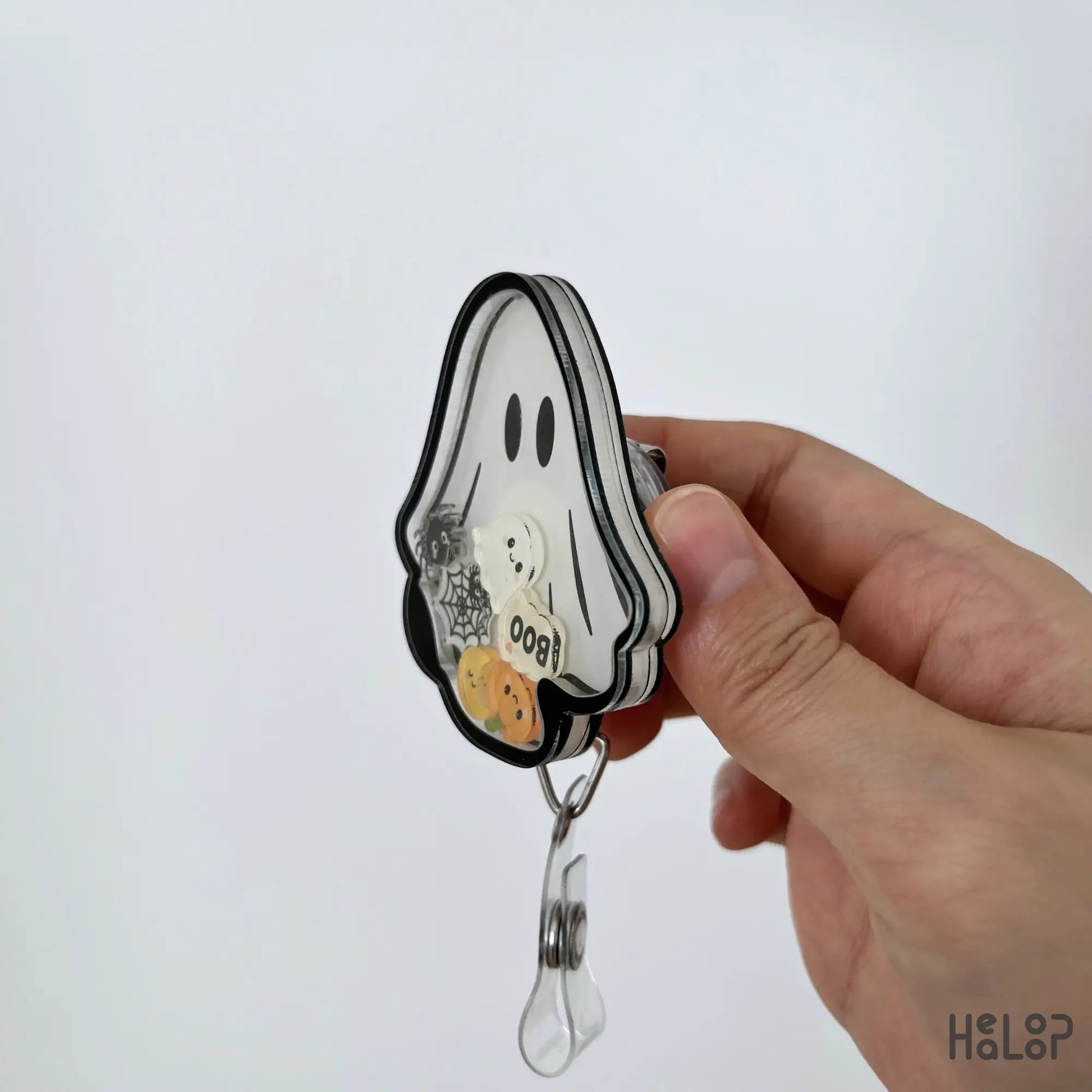 Side profile of handmade Ghost Halloween shaker badge reel showing layered acrylic design
