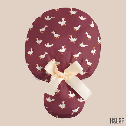 Goose Ponytail Scrub Cap shown from the back, featuring a burgundy goose print, cream ribbon bow, and a spacious pouch designed for long hair.