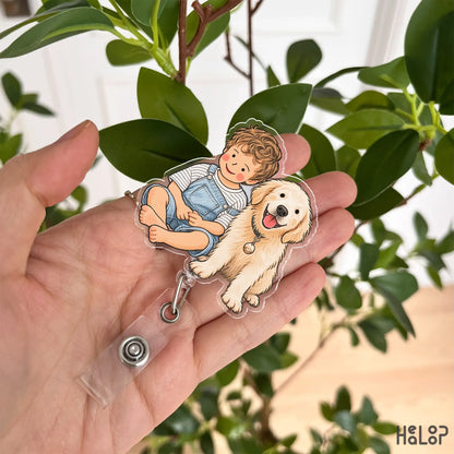 Close-up of a HEALOOP personalized portrait badge reel held in a hand, featuring a boy and golden retriever in a custom hand drawn design.
