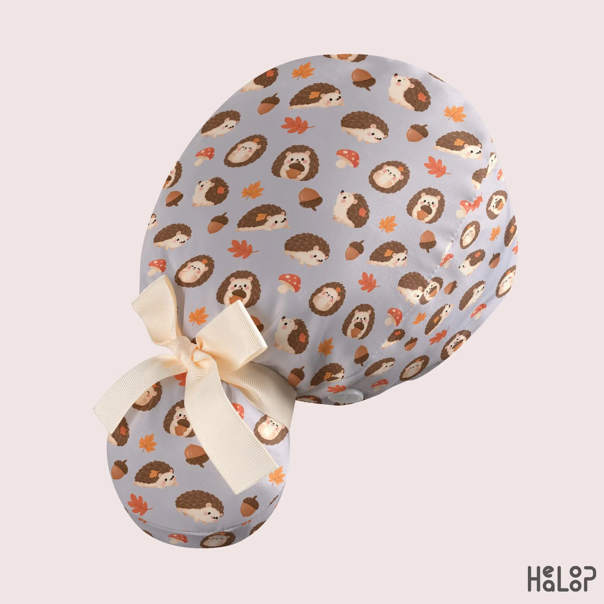 Hedgehog ponytail scrub hat side profile showing soft gray woodland print fabric, spacious ponytail pouch, and adjustable cream ribbon bow.