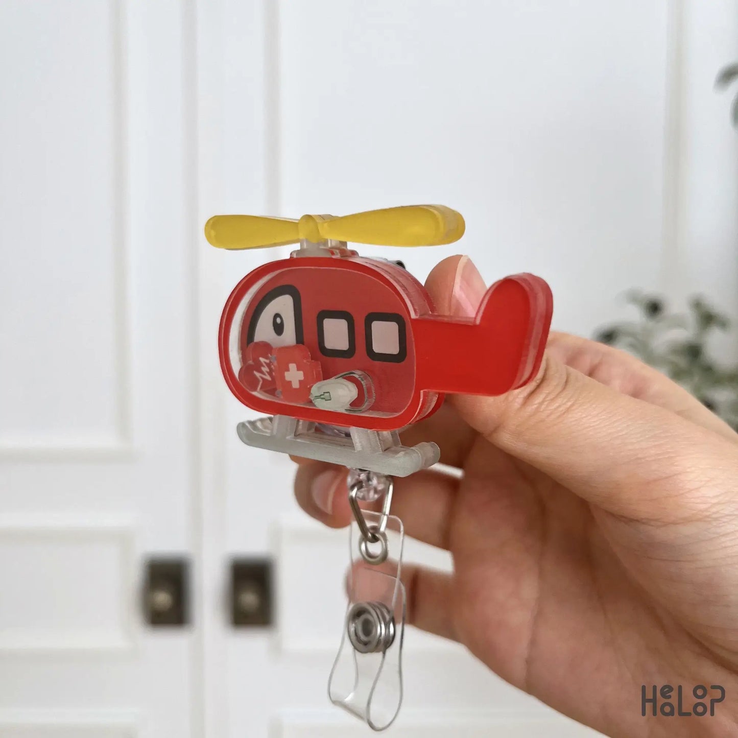 Layered acrylic helicopter shaker badge reel showing its durable construction and movable medical-themed charms.