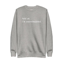 Flat lay of 'Hold on... I’m overstimulated' sweatshirt in Carbon Grey with premium embroidered text design, perfect for mental health awareness.