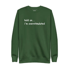 Flat lay of 'Hold on... I’m overstimulated' sweatshirt in Forest Green with high-quality embroidered text, perfect for casual wear and mental health advocacy.