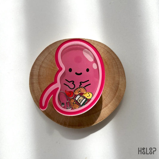 Kidney-shaped pink shaker phone grip with tiny charms placed on wooden tray
