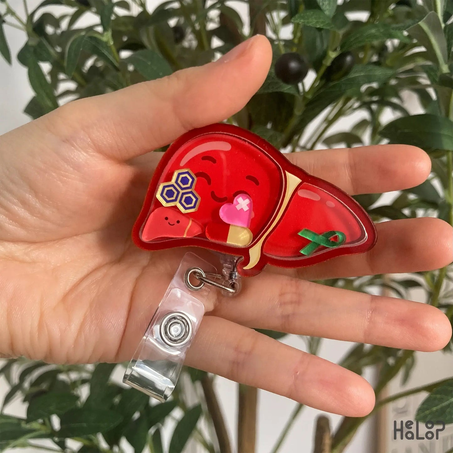 Liver Shaker Badge Reel – cute red liver design with smiling face held in hand