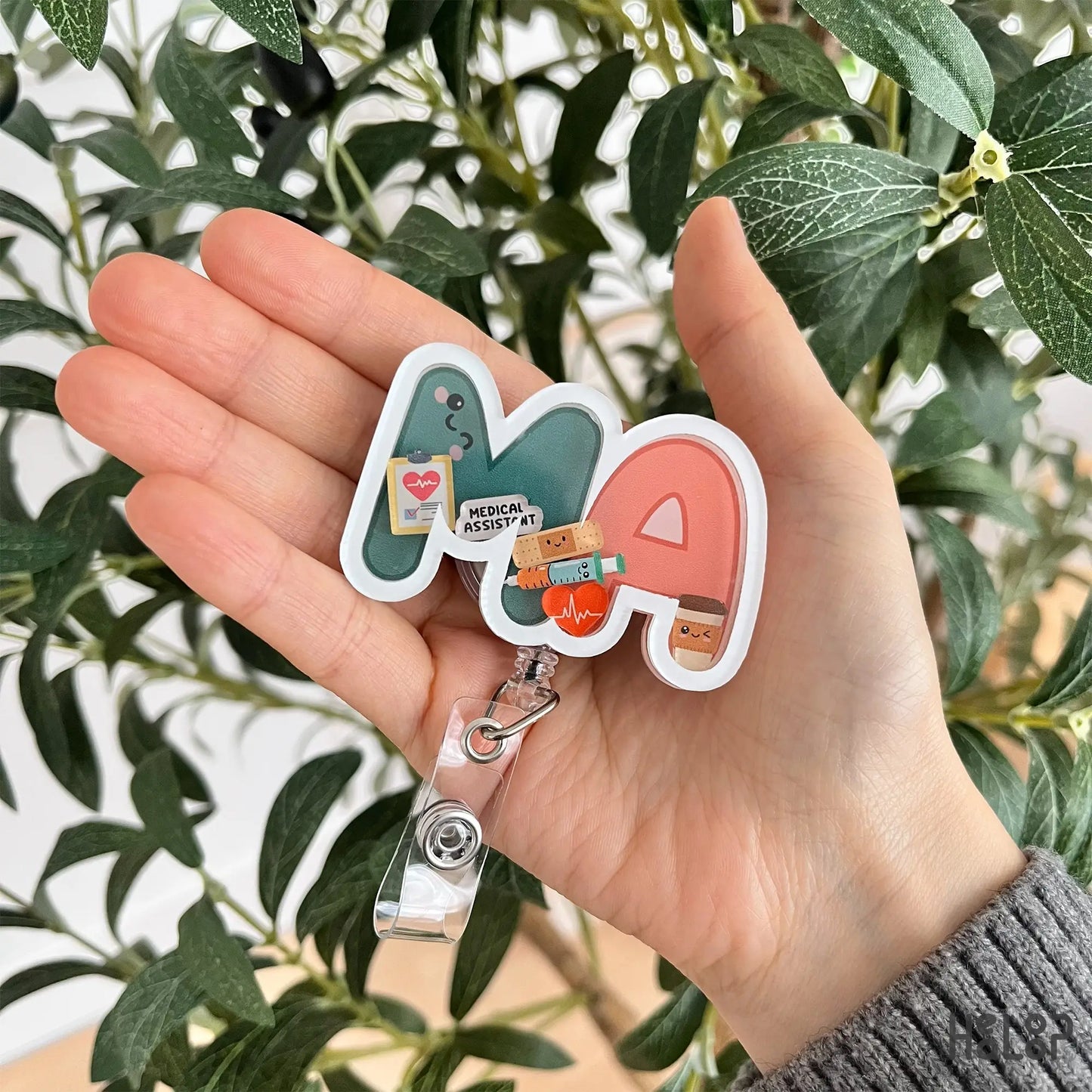 MA shaker badge reel shown in hand for size reference and everyday wear