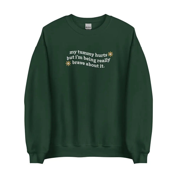 Flat lay of My Tummy Hurts sweatshirt in Forest Green with embroidered text, 'My tummy hurts but I'm being really brave about it'