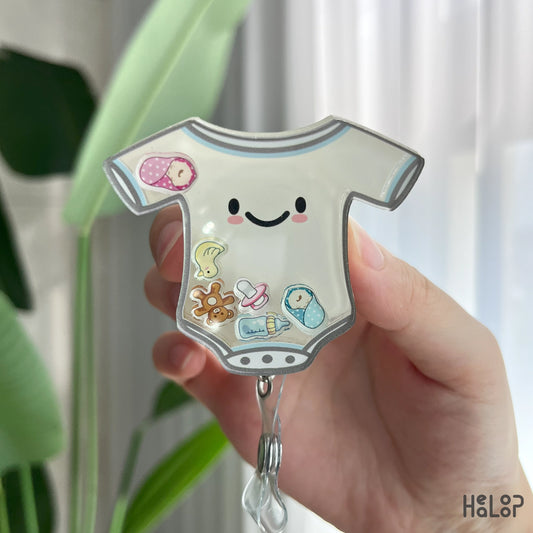 Detailed view of NICU shaker badge reel with pacifier, swaddled babies, teddy bear, and bottle