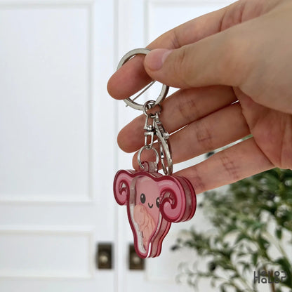 Side view of Healoop OBGYN shaker keychain showing the layered acrylic design and baby charm