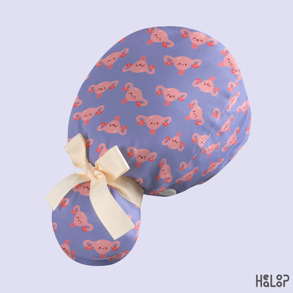 Side view of HEALOOP OBGYN Uterus Ponytail Scrub Cap featuring a lavender and pink uterus pattern, cream ribbon tie and ponytail-friendly design.