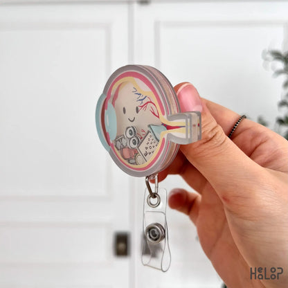 Layered acrylic ophthalmology shaker badge reel shown from side angle with clear retractable clip.