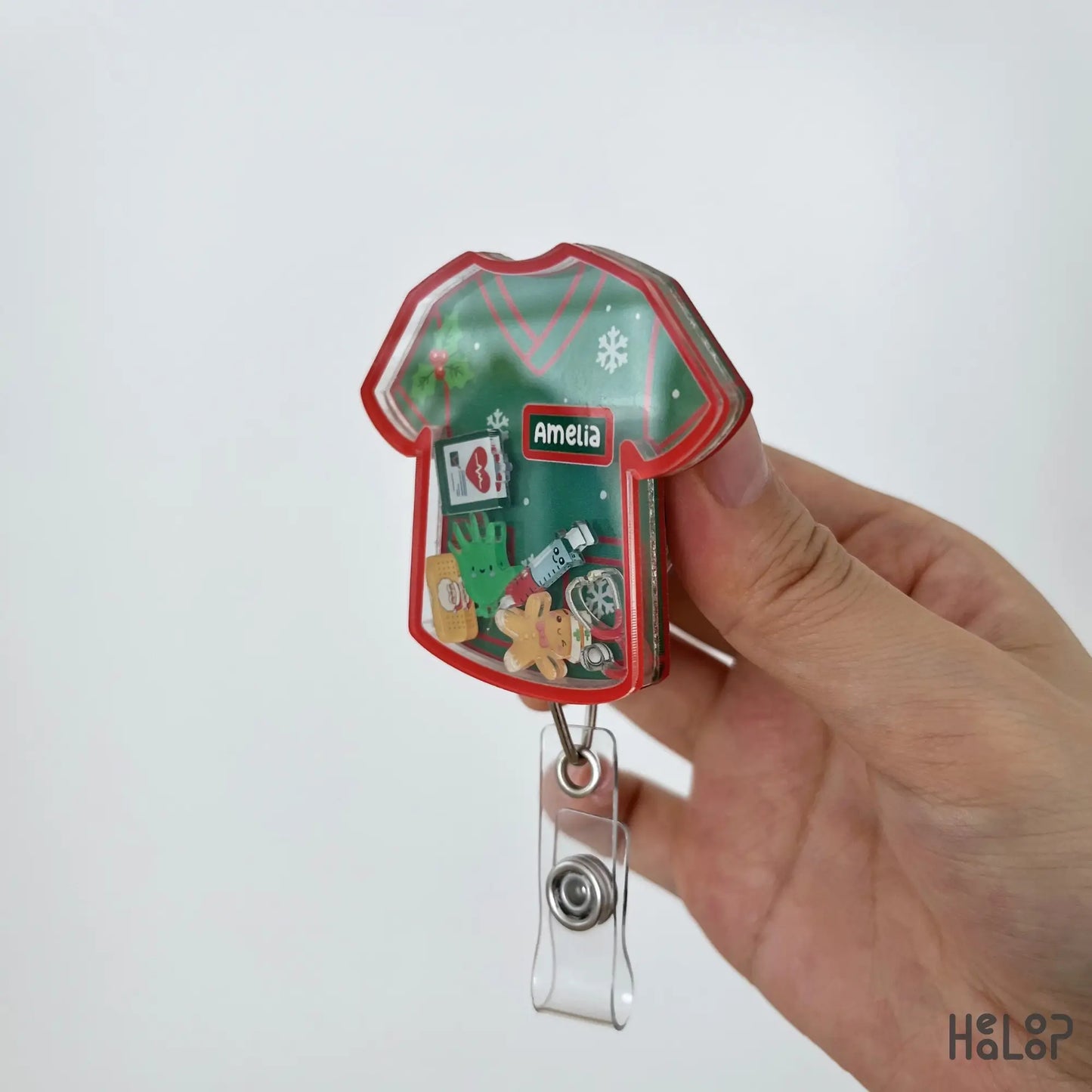 Side view of a personalized Christmas scrub shaker badge reel showing layered acrylic construction.