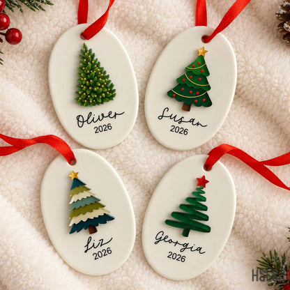 Personalized Christmas tree ornaments featuring oval ceramic bases, raised acrylic trees, custom names and year