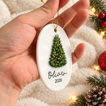 Personalized Oliver Christmas ornament with ceramic base and raised Christmas tree shown held in hand