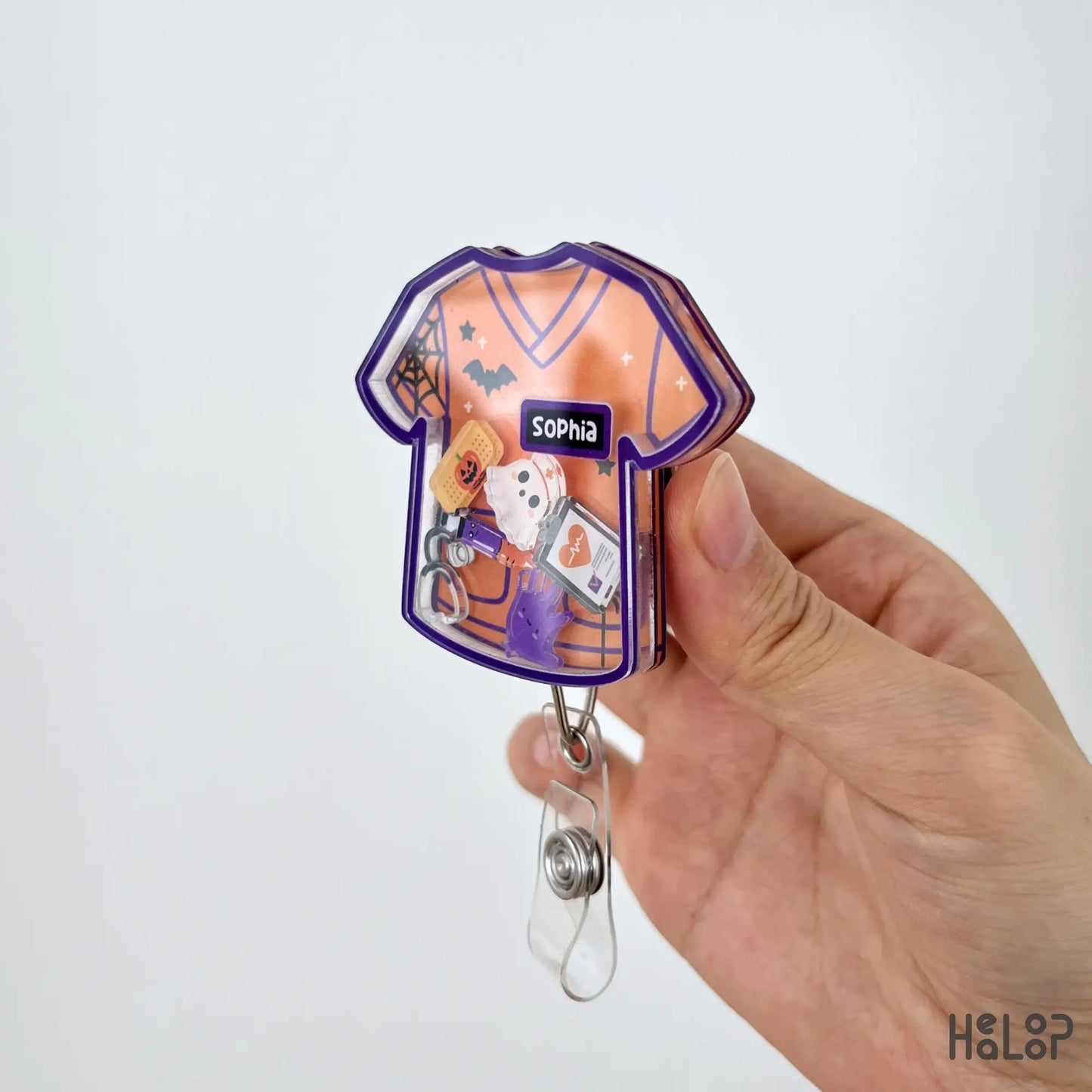 Side view of a personalized Halloween scrub shaker badge reel showing layered acrylic construction.