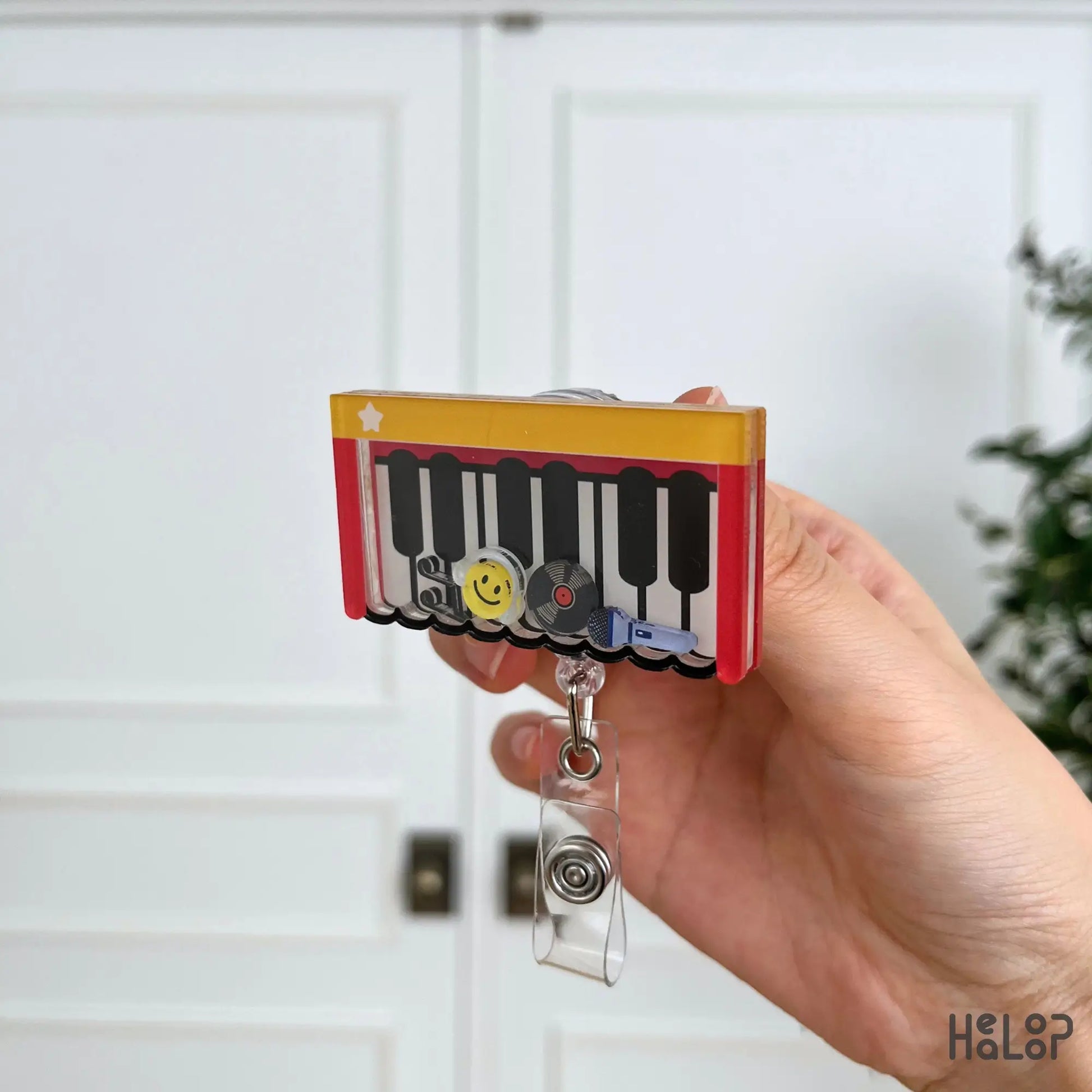 Side profile of the layered acrylic Piano Shaker Badge Reel highlighting its shaker depth and movable music-inspired charms.