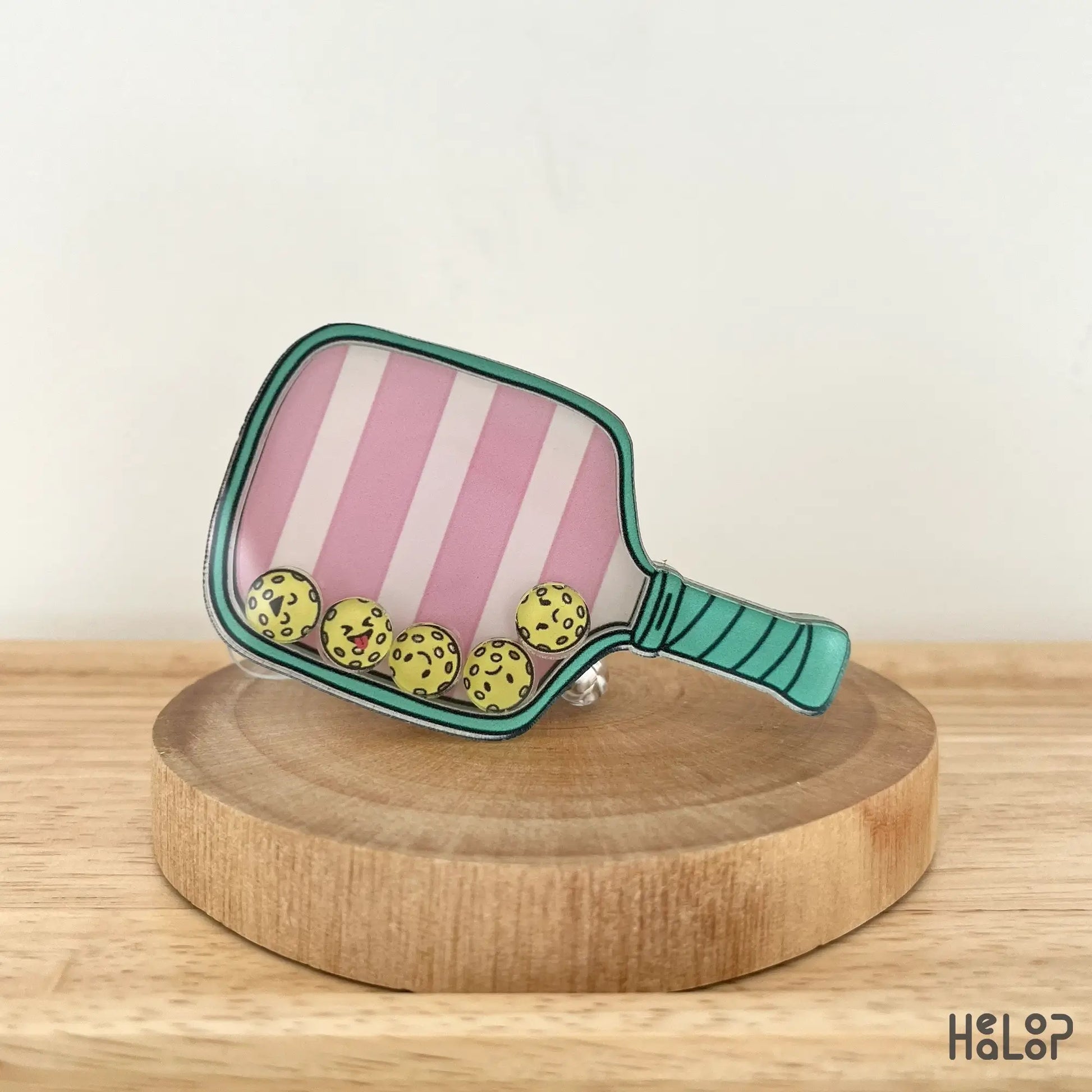 Angled view of cute pink paddle badge reel with floating pickleballs