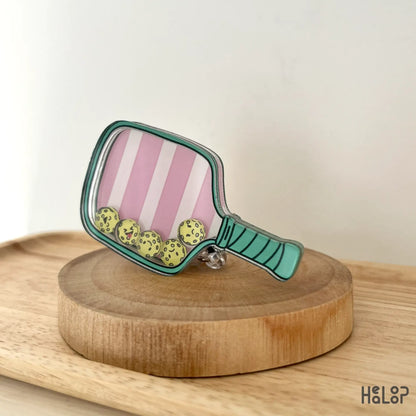 Close-up of fun pickleball-themed shaker badge reel on wooden display