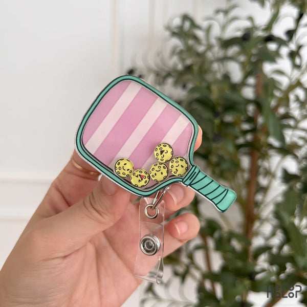 Front view of pickleball paddle badge reel with shaker pickleballs