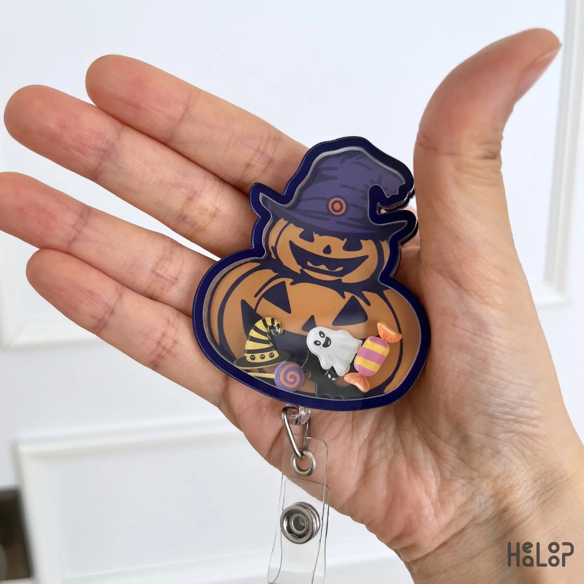Detailed close-up of Pumpkin Halloween acrylic shaker badge reel with moving spooky charms