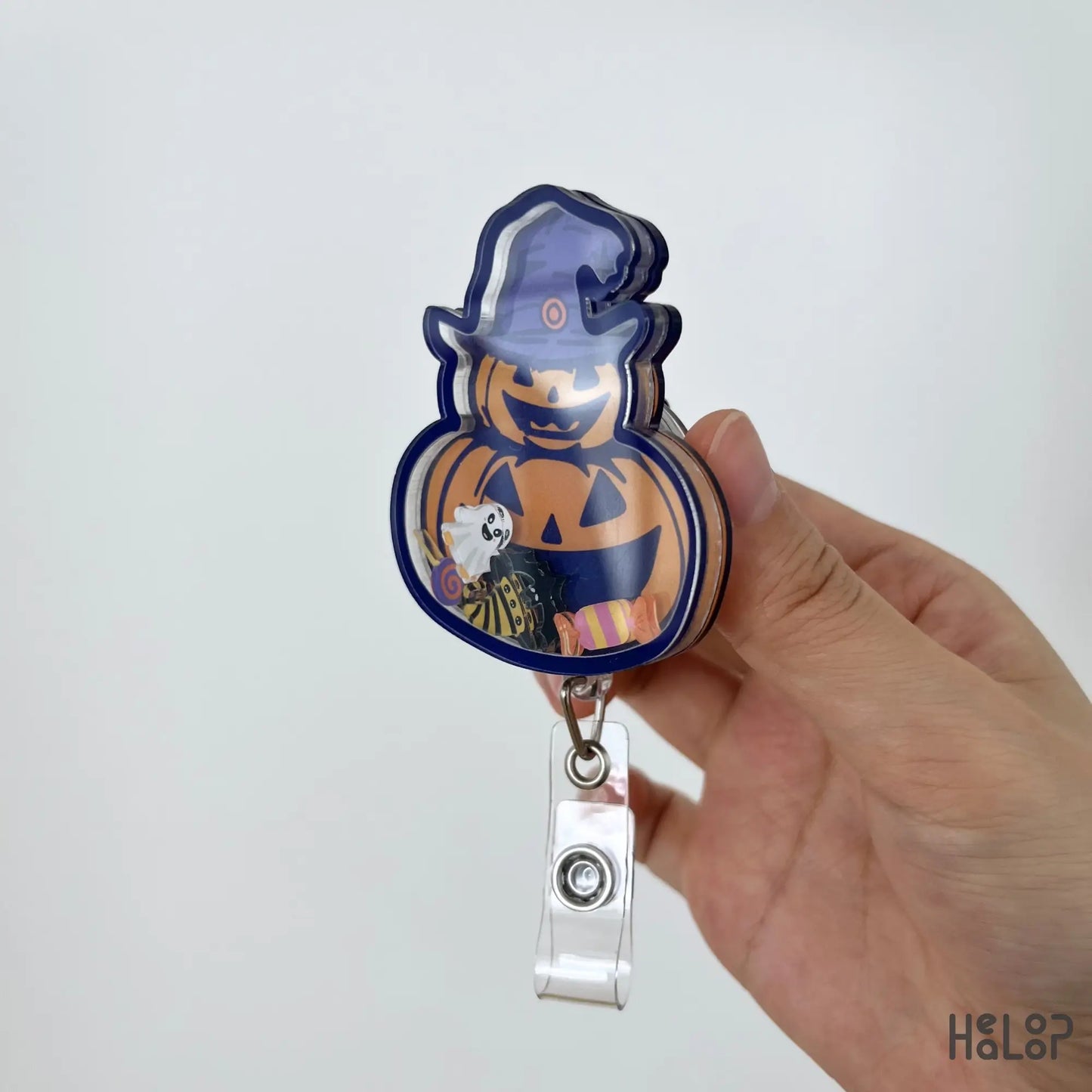 Side profile of handmade Pumpkin Halloween shaker badge reel showing layered acrylic design